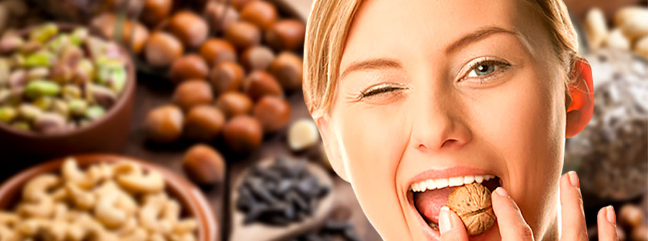 Femme croquant une noix avec un clin d'œil, entourée de noisettes, pistaches et noix de cajou, pour SANUSq Health