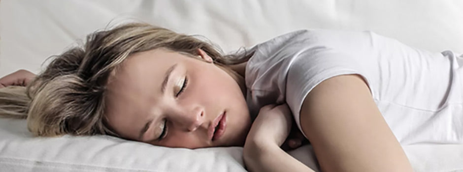Jeune femme faisant une sieste paisible sur des draps blancs, pour l'énergie et la récupération – SANUSq Health