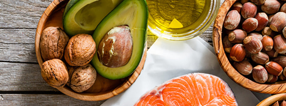 Bonnes graisses : avocat, noix, noisettes, huile d'olive et saumon frais sur une table en bois – SANUSq Health
