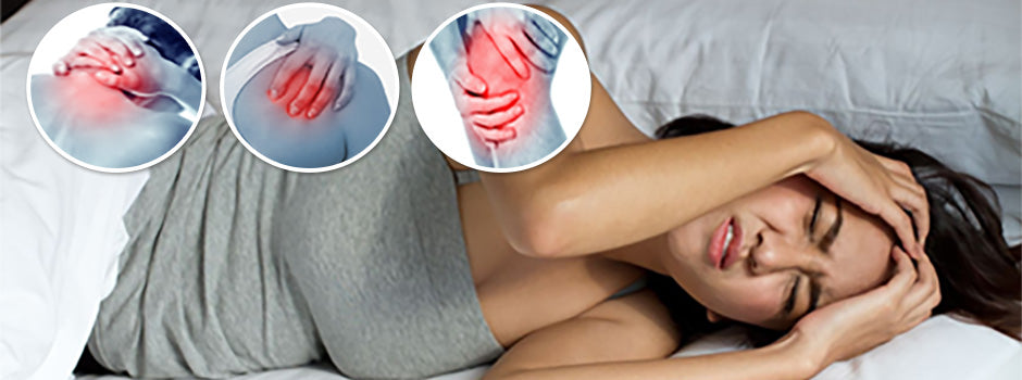Femme au lit se tenant la tête de douleur, avec des douleurs à l'épaule, à la hanche et au genou liées à la fibromyalgie – SANUSq Health