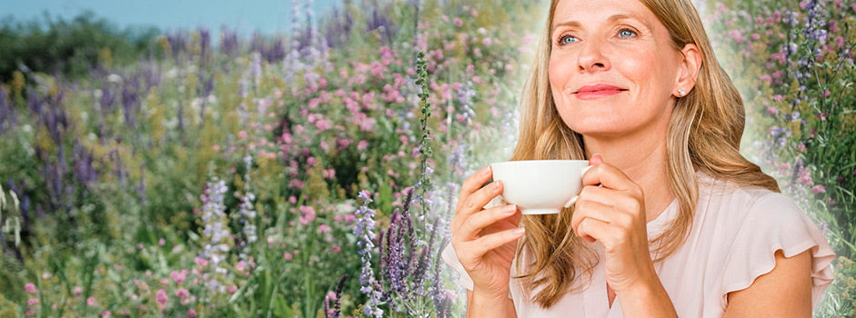 Femme sereine savourant une tisane dans un jardin fleuri, évoquant les plantes anti-stress — SANUSq Health