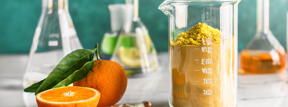 Oranges et poudre de vitamine C dans un bécher entouré de matériel de laboratoire — SANUSq Health