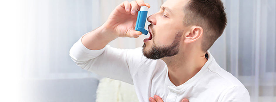 Homme utilisant un inhalateur contre l'asthme, la main sur la poitrine, par SANUSq Health sur la vitamine D et l'asthme