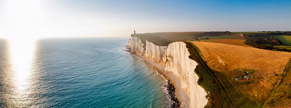 Falaises de craie blanche au soleil doré au-dessus d'une mer calme, symbole de la vitamine D3, de la K2 et du calcium
